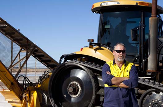 An image of a man with his arms crossed standing in front of machinery.